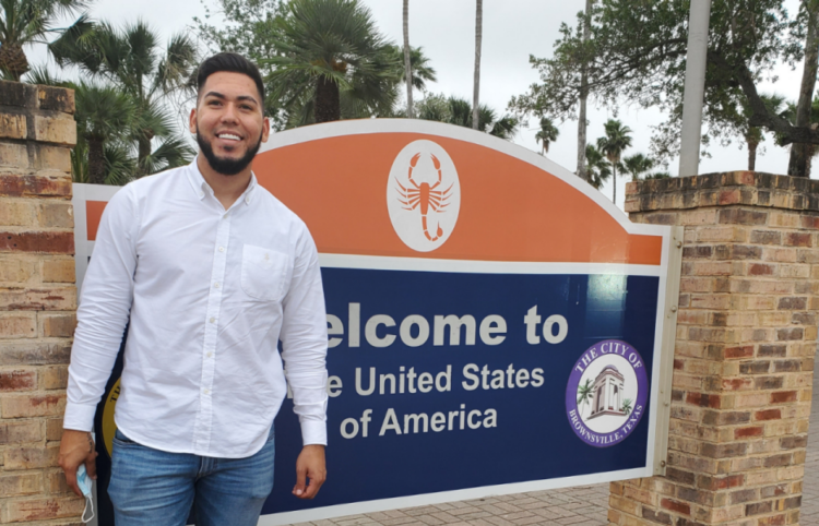 Happy young male ProBAR client in front of Welcome to the United States of America sign.