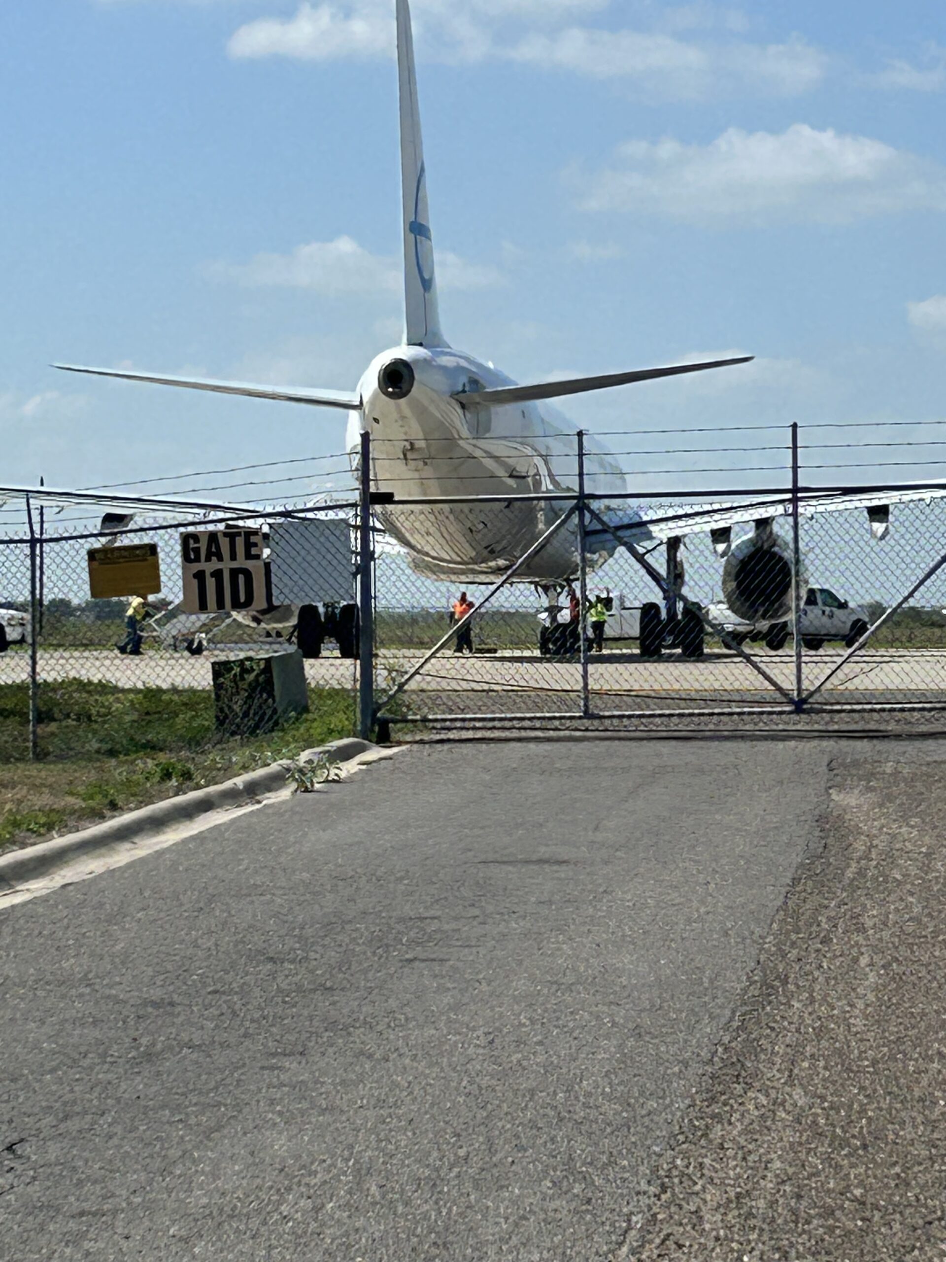 an airplane readies for takeoff behind a chain link fence gate.